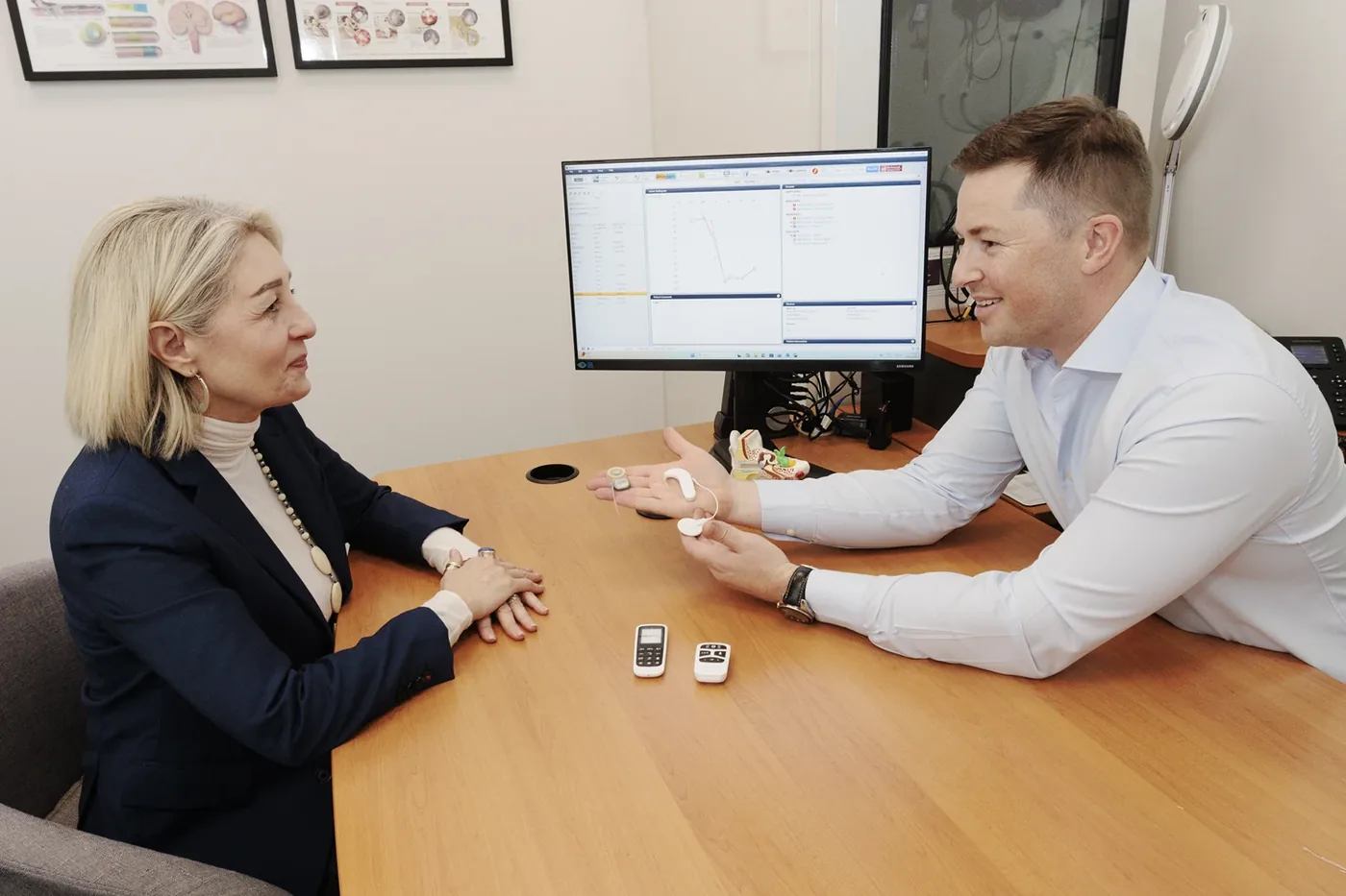 An audiologist talking a patient through hearing aid options at the clinic.