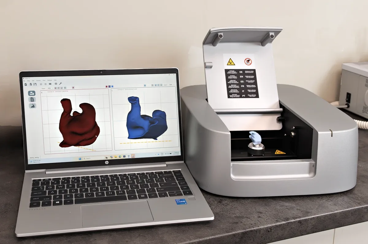 A scanner and laptop showing a three-dimensional scan of an ear, used to make custom moulds.