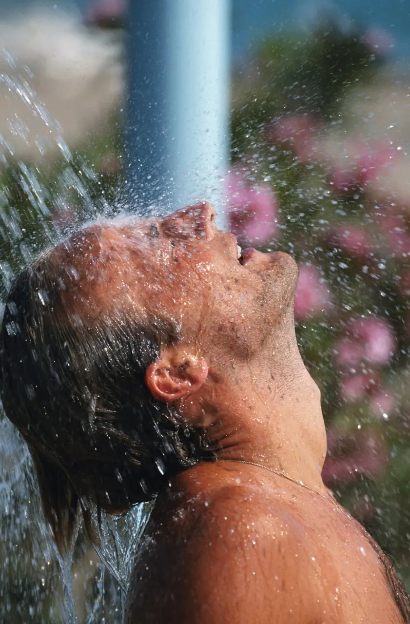 A man tipping his head back under an outdoor shower, from Phonak's Lyric campaign.