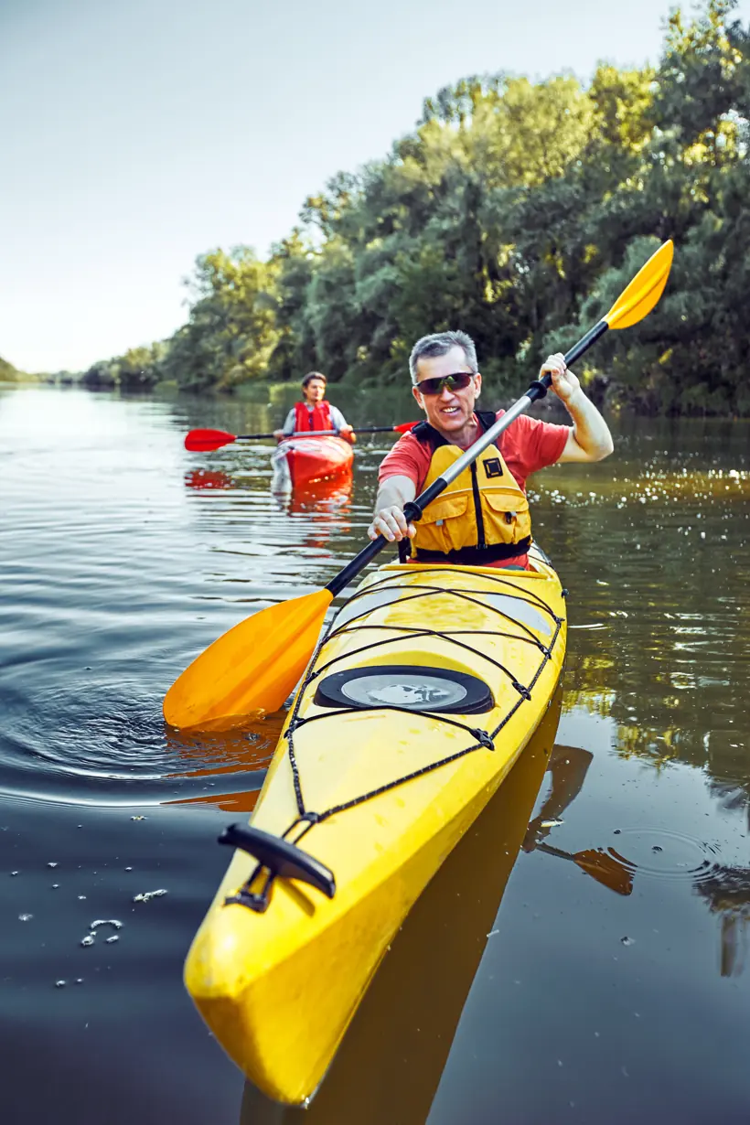 A man kayaking on a river, from Phonak's Lyric campaign.